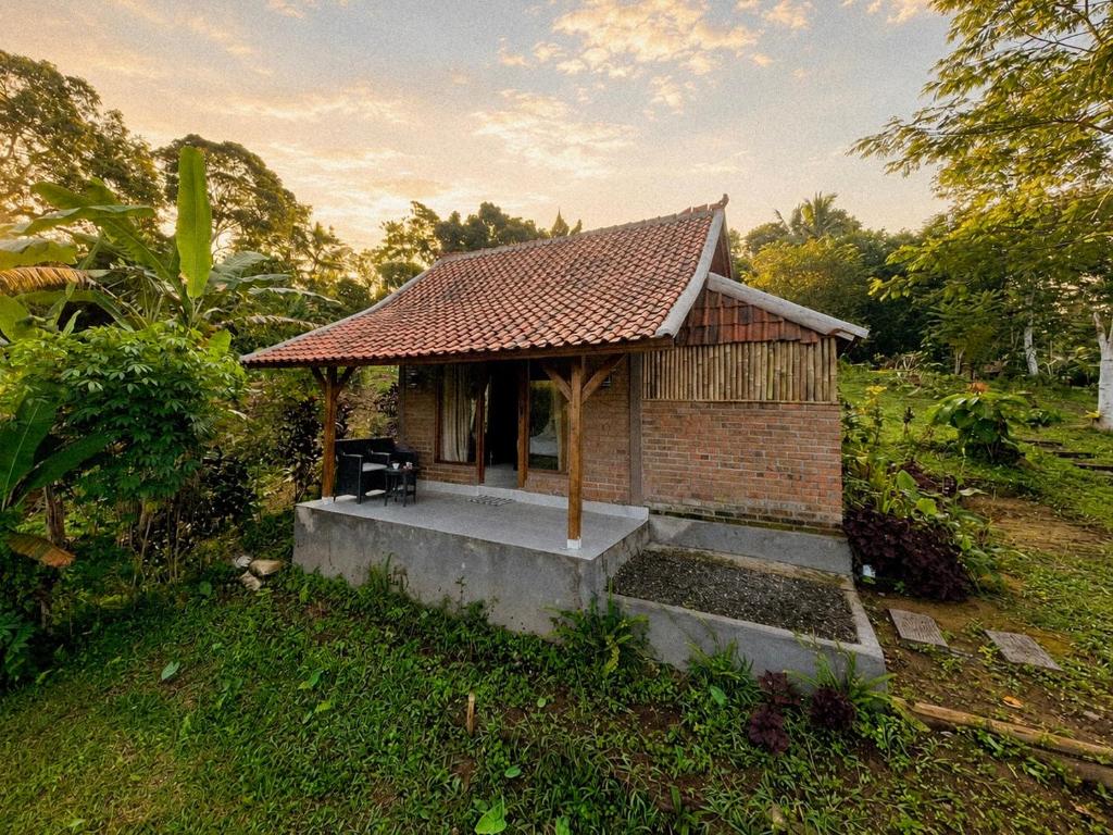 a small building with a roof on a field at Tuka Cabins in Jatiluwih