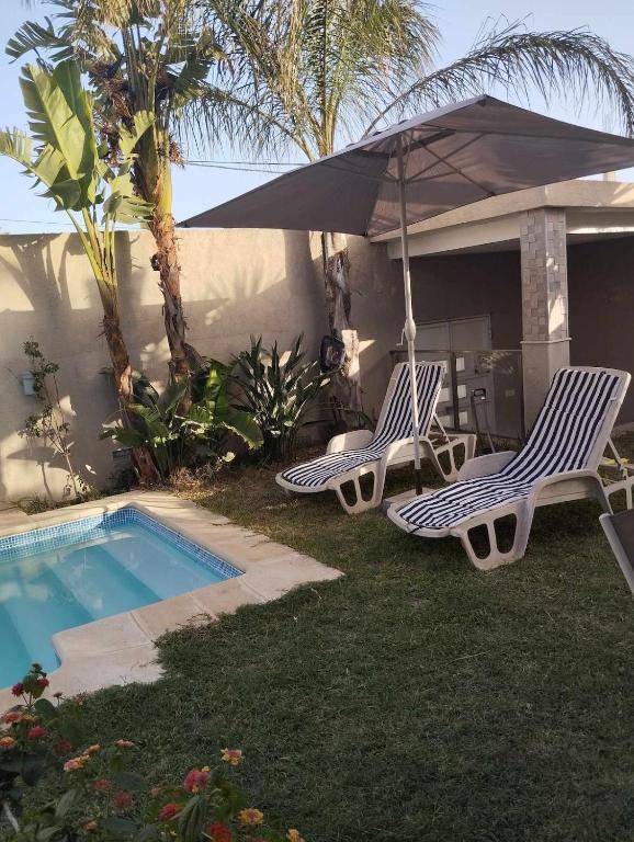 two chairs and an umbrella next to a swimming pool at Beautiful villa with pool KELIBIA in Kelibia