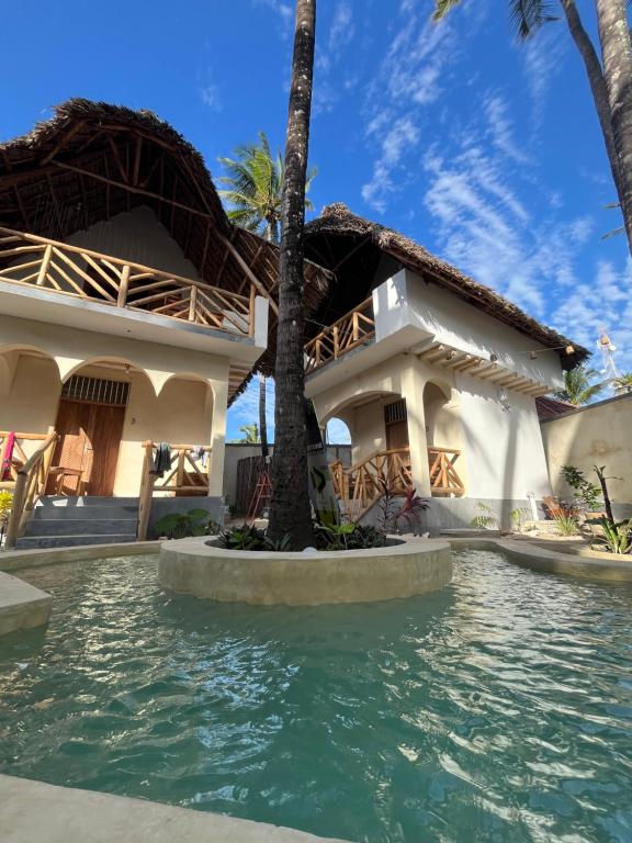 a house with a swimming pool in front of it at Jambiani Kite Lodge in Jambiani
