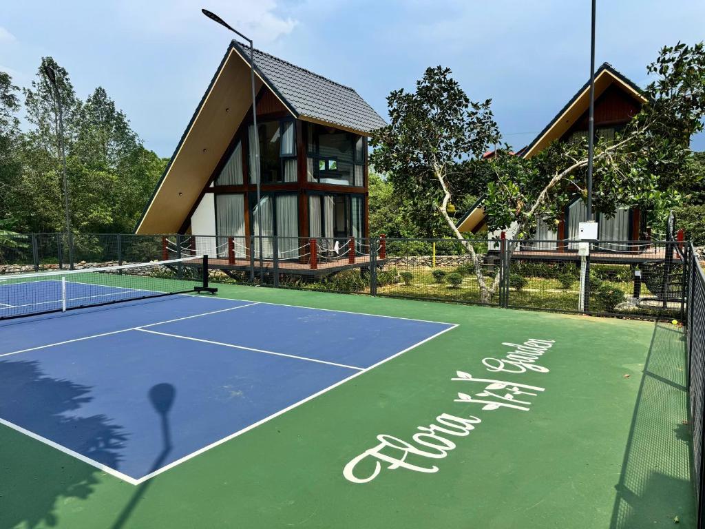 a tennis court with a house in the background at Flora Garden in Làng Hang
