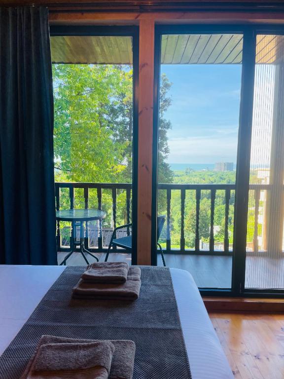 a bedroom with a bed and a balcony with a view at GrapeHill Cottage in Achʼqva