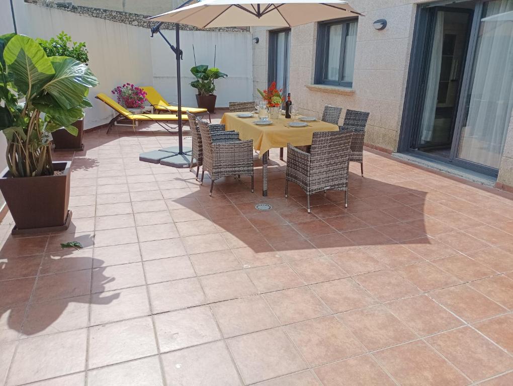 a patio with a table and chairs and an umbrella at Apartamento La Camelia in Rosal