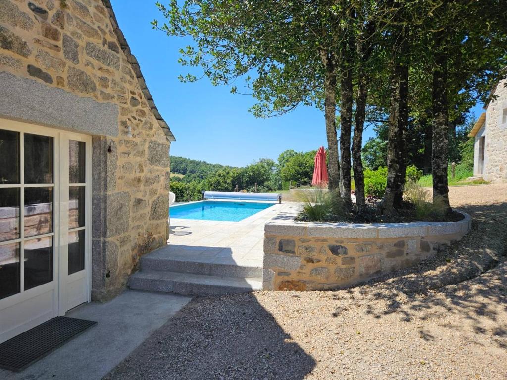 a stone building with a door and a swimming pool at La Borie de Peyrot in Huparlac