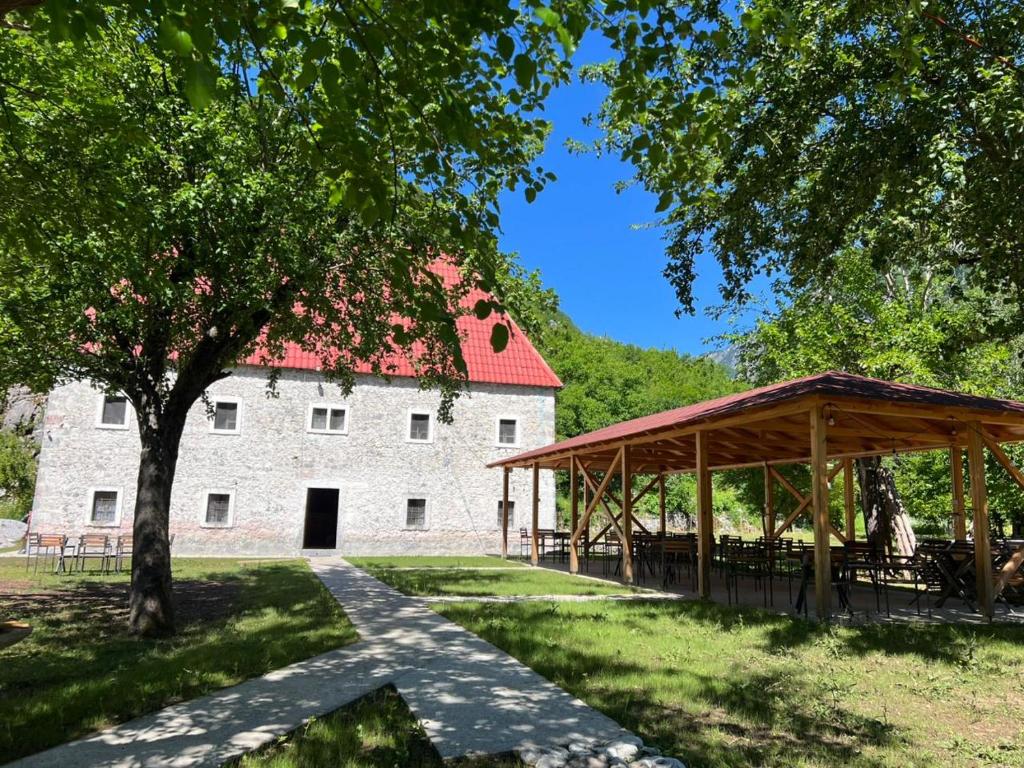 a pavilion in front of a large stone building at Bujtina Shpjia e Gjyshit in Ndërlysaj