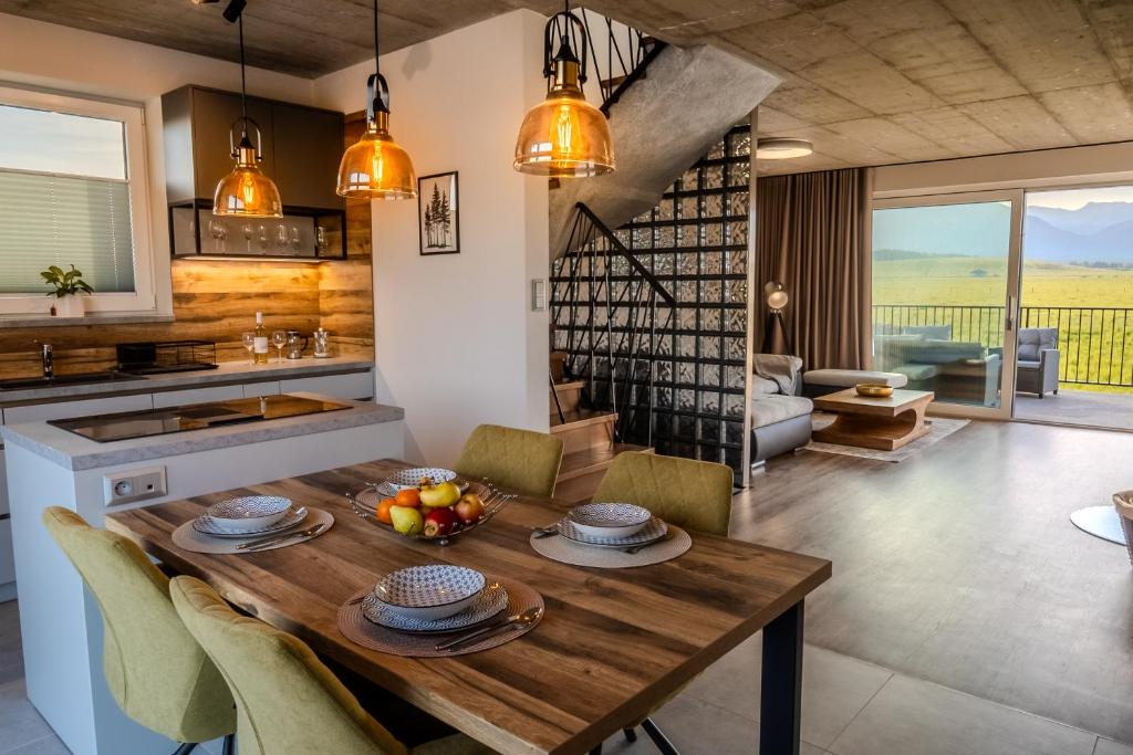a kitchen and living room with a wooden table and chairs at LomniSki apartment in Veľká Lomnica