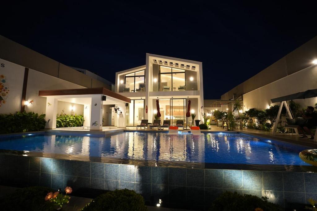 a large swimming pool in front of a house at night at Blooms Villa in Al Rama