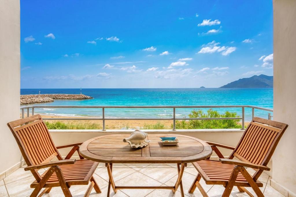 a table and two chairs on a balcony with the ocean at Komi Shoreline Blue Window in Kómi