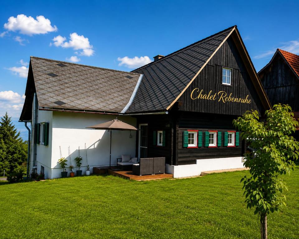 a black and white house with a grass yard at Chalet Rebenruhe Südsteiermark in Praratheregg