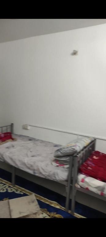 a bed in a room with a white wall at Living room in Muscat