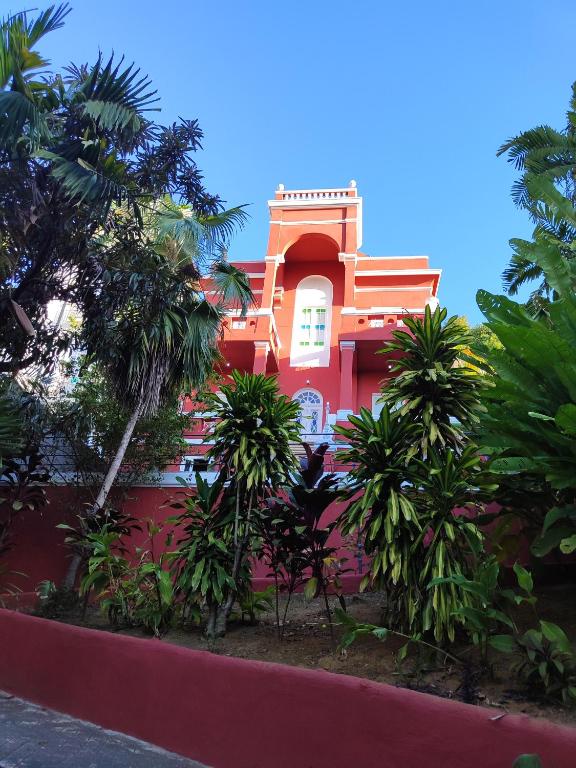 a red building with palm trees in front of it at Guesthouse Villa Dourada in Rio de Janeiro