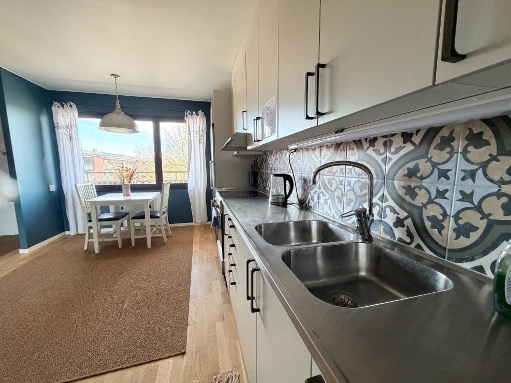 a kitchen with a stainless steel sink and a table at Lysekil Apartment Hotel in Lysekil