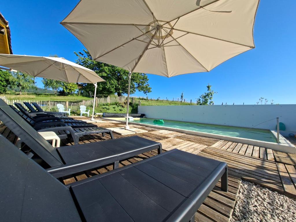 a group of chairs and umbrellas next to a swimming pool at Chambres d'hotes aux Petits Belézins in Saint-Amour