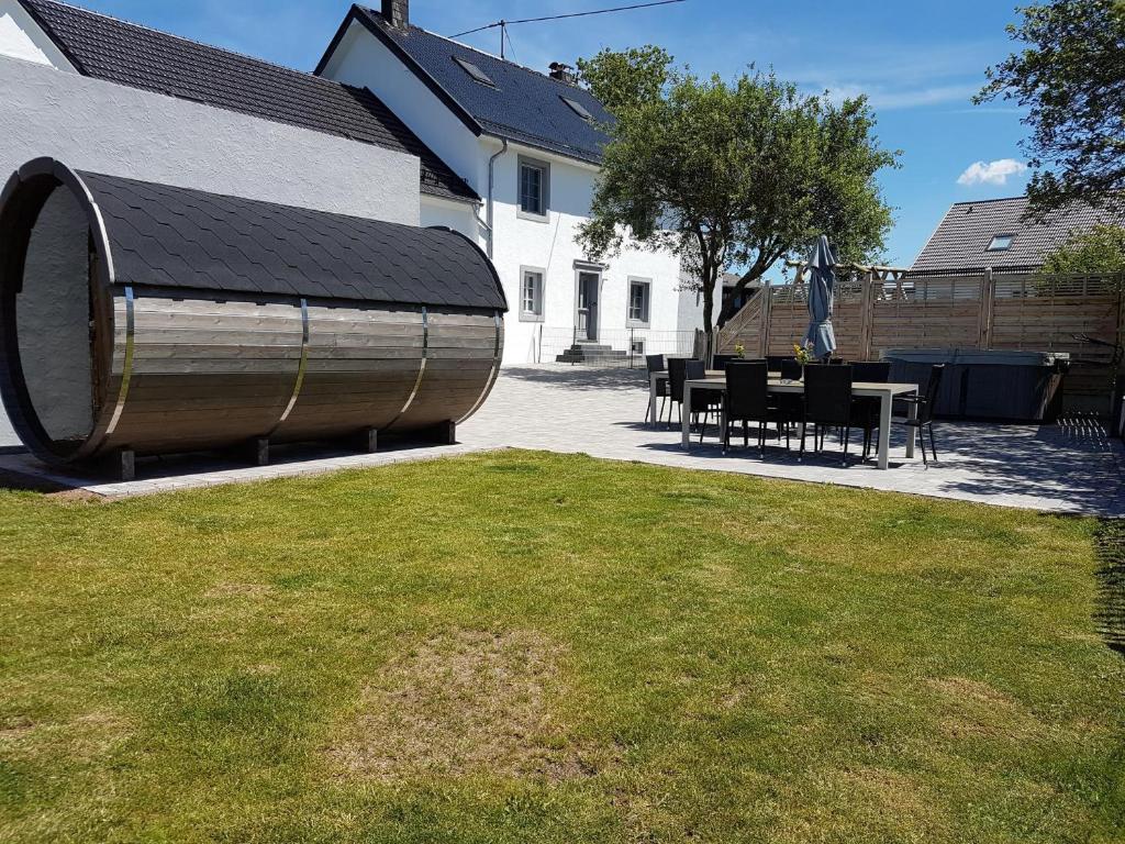 a yard with a table and chairs and a building at Eifel-Dream Schneifelhaus in Kobscheid