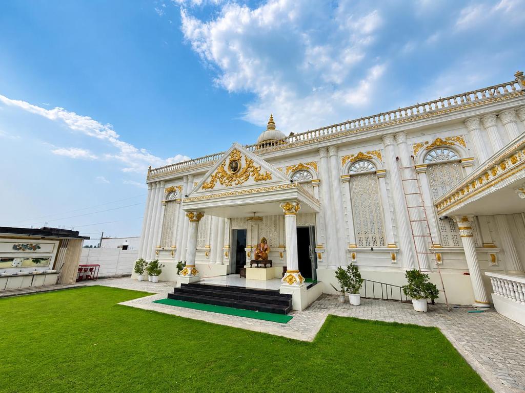 a large white building with a green yard at Hotel SR Vivanta,Brahmapur in Brahmapur