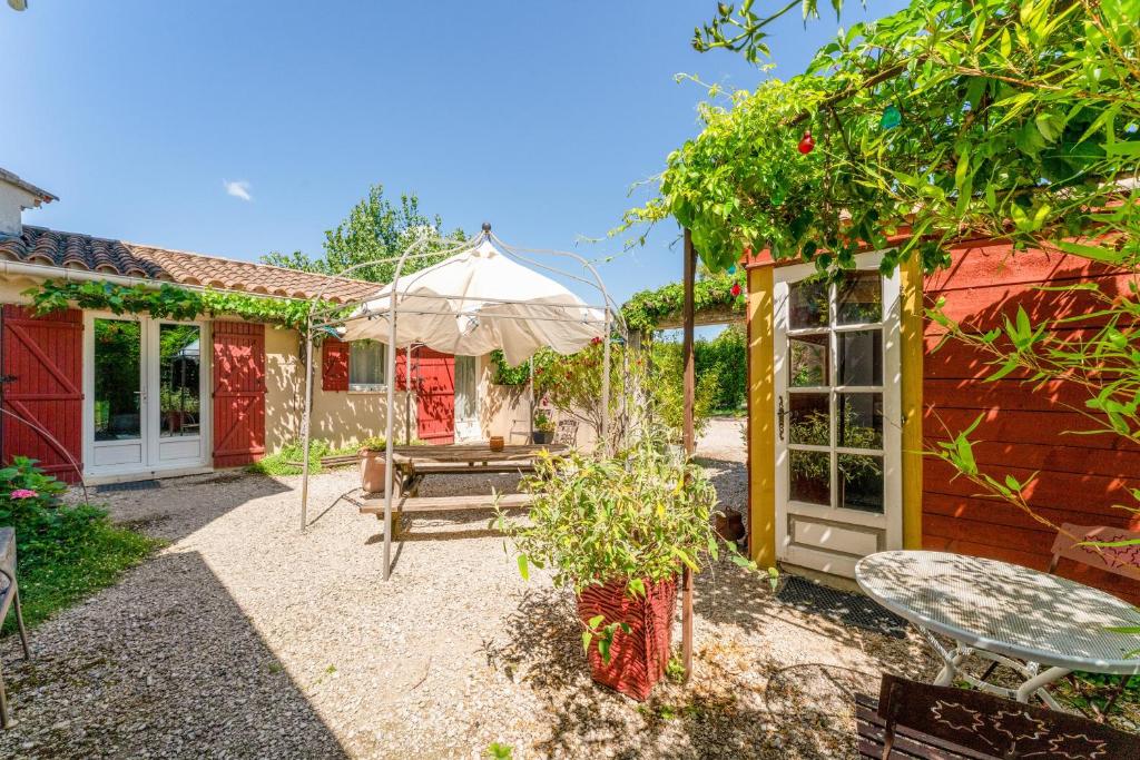 a patio of a house with a table and a tent at Chambres D'hôtes Les Seignerolles in Pernes-les-Fontaines