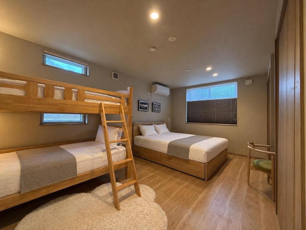 a bedroom with two bunk beds and a chair at Koyuki Kimobetsu in Abuta