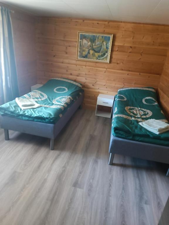 two beds in a room with wooden walls at Aurora appartmens in Senja