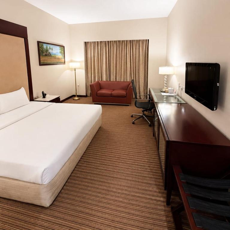 a hotel room with a large bed and a chair at Silka Maytower Kuala Lumpur in Kuala Lumpur