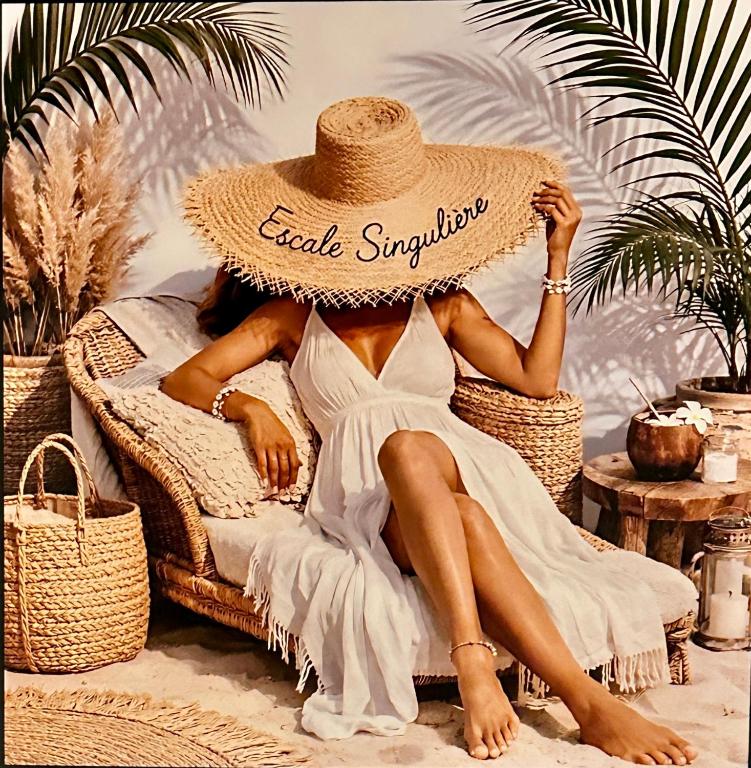 a woman in a straw hat sitting in a chair on the beach at Escale Singulière - Balnéo, patio et confort 4 étoiles in Sète