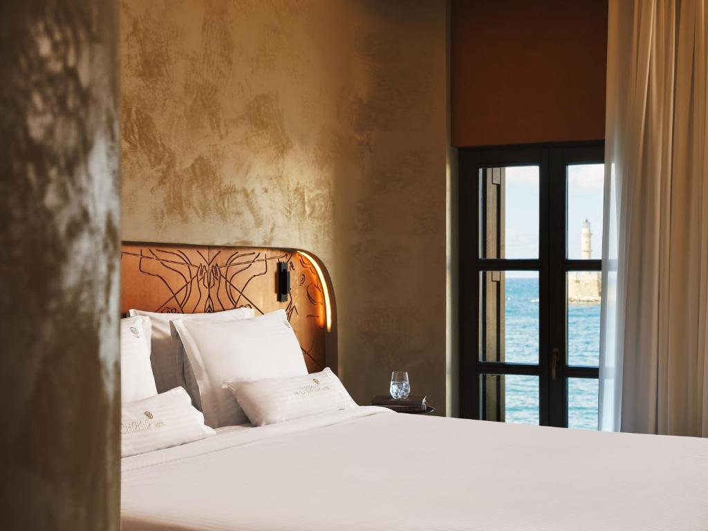 a bedroom with a white bed with a window at Porto Antico in Chania