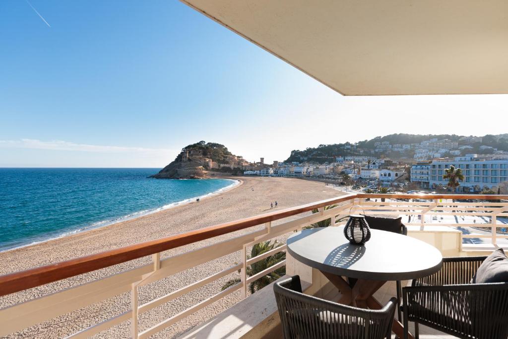 a balcony with a table and chairs and a beach at Lets Holidays INCREDIBLE APARTMENT WITH AMAZING VIEWS in Tossa de Mar