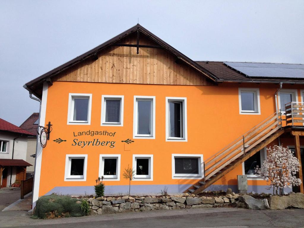 ein orangenes Haus mit einem Schild an der Seite in der Unterkunft Landgasthof Seyrlberg in Reichenau im Mühlkreise