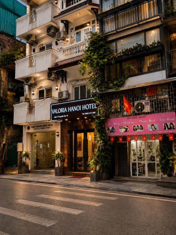 a building with a sign for a hotel on a street at Valoria Premium Hanoi Hotel and Travel in Hanoi