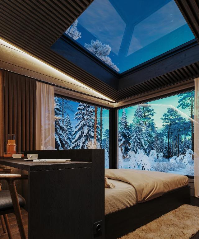 a bedroom with a large window with snow covered trees at ALVA Resort in Rovaniemi