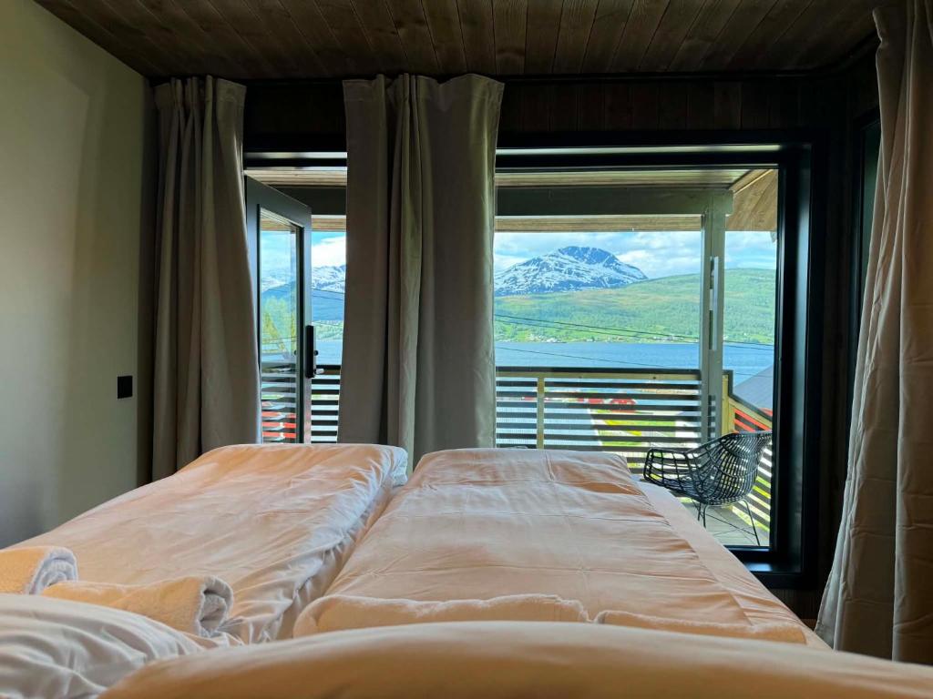 a bedroom with two beds and a large window at Aa-Gård in Tennevoll