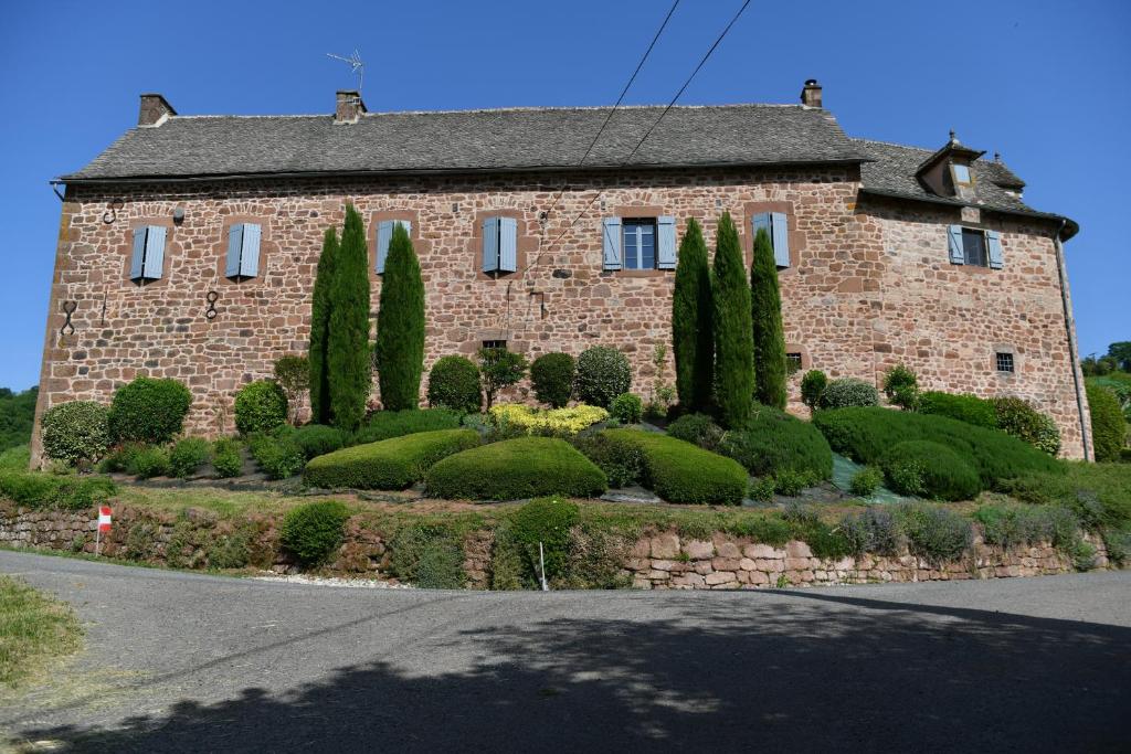 a large brick house with trees in front of it at Sans Chichi Chambres Et Table in Escandolières