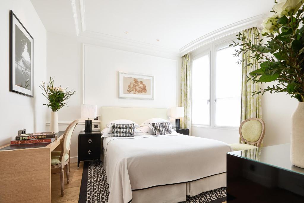 a white bedroom with a bed and a window at Grand Hôtel Du Palais Royal in Paris