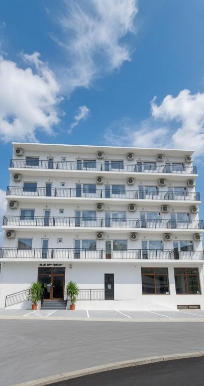 a large white building with windows on a street at Blue Sky Hotel in Eforie Nord