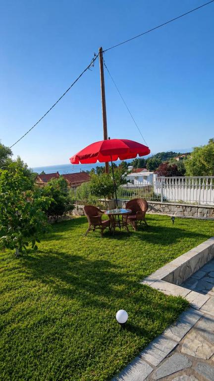 a picnic table with a red umbrella in a yard at red caravan in Nea Potidaea