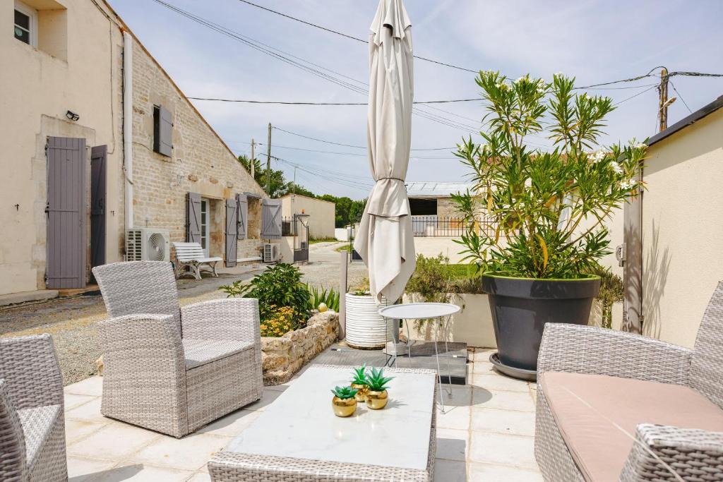 a patio with a table and chairs and an umbrella at Gite Romantique de Type Charentais in Le Thou