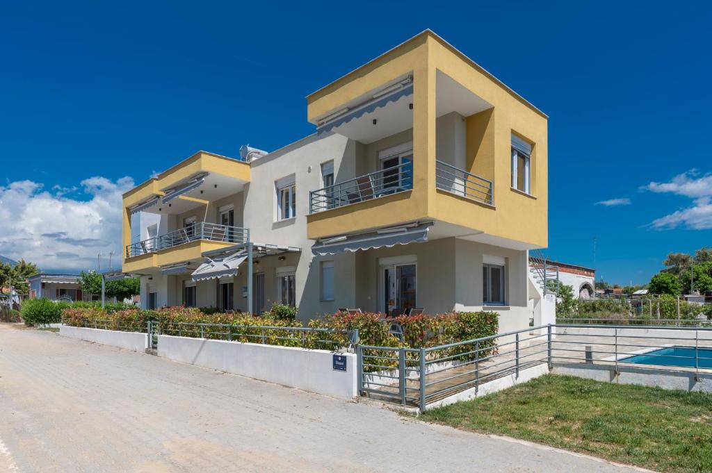 a large yellow and white building on a street at SLV Danai 7 Apartments in Ofrínion
