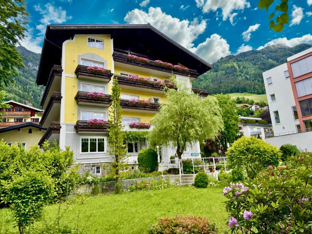 a yellow and white building with flowers on the balconies at MÜHLBACHER - inklusive kostenfreiem Eintritt in die Alpentherme in Bad Hofgastein