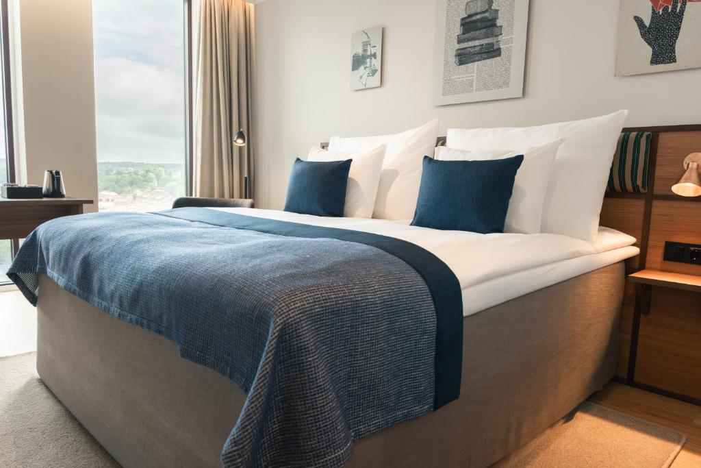 ein Schlafzimmer mit einem großen Bett und blauen und weißen Kissen in der Unterkunft Quality Hotel The Book in Göteborg
