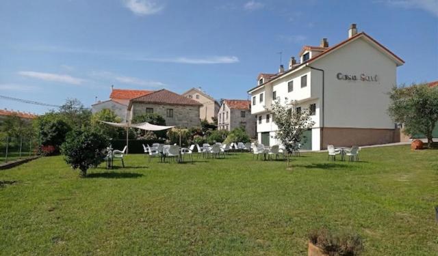 a lawn with chairs and a building with a sign on it at Casa Savi in Miño