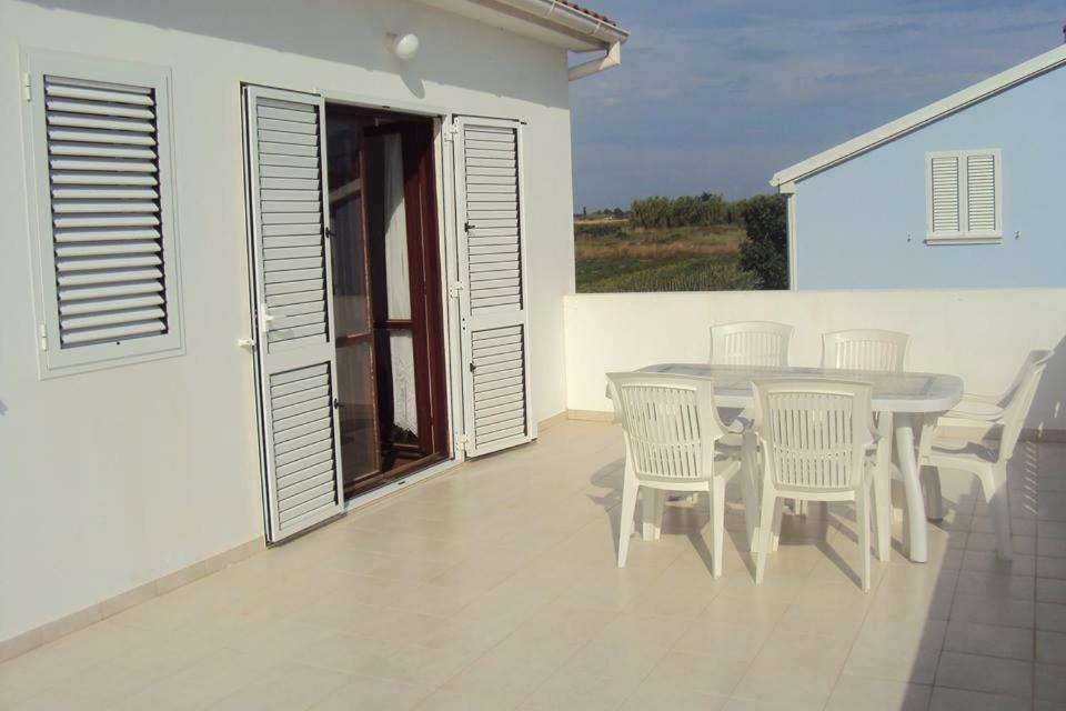 a dining room with a table and chairs on a balcony at Apartments Marko in Vrsi