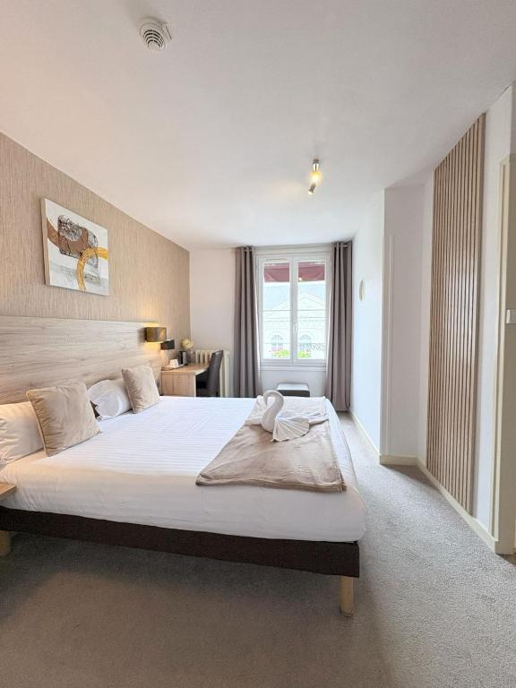 a bedroom with a large white bed in a room at Hôtel L'Univers in Châtellerault