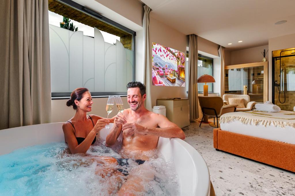 a man and woman sitting in a bathtub in a hotel room at Suite romantique Ibiza, Jacuzzi, Spa in Strasbourg