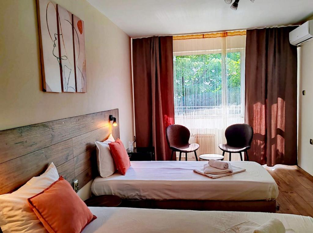 a hotel room with two beds and a window at Hotel Sorbona in Varna City