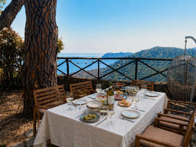 a table with plates of food and wine glasses at Riviera Panorama Retreat in Alassio