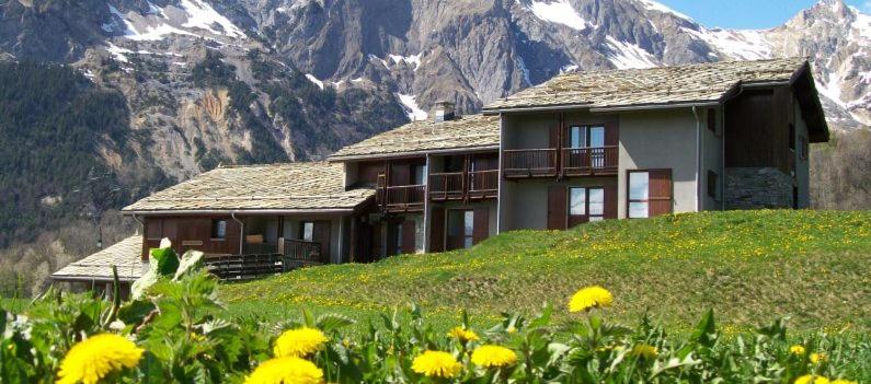 a house on a hill with a field of yellow flowers at Le Shantoné in Saint-Michel-de-Maurienne