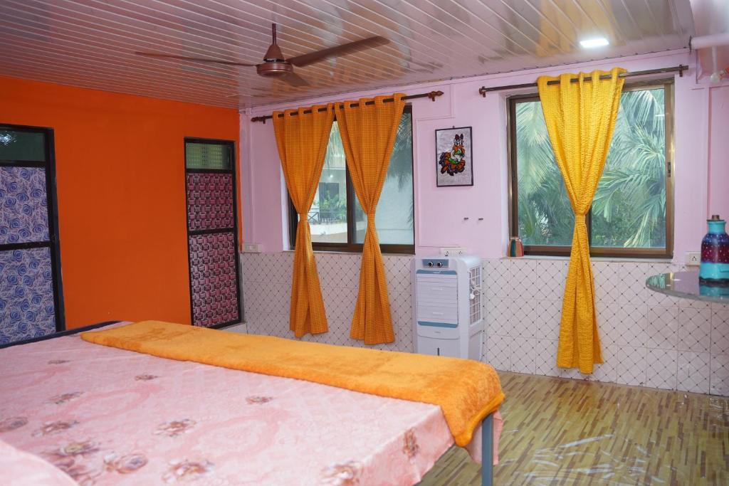 a bedroom with orange curtains and a bed in a room at Dr Vijeta's Wellness Retreat in Alībāg