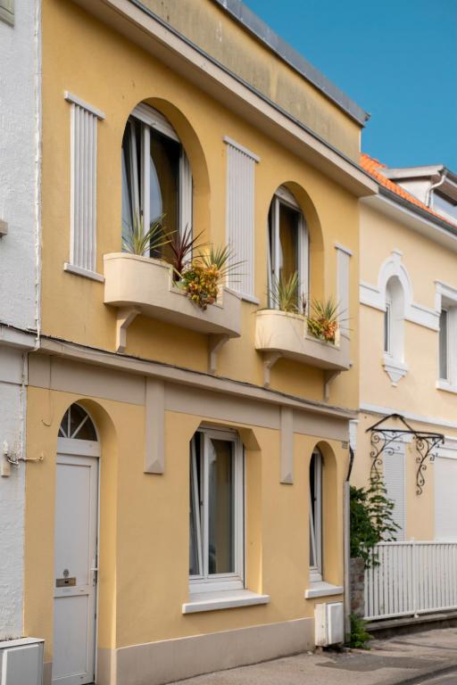 a yellow building with windows and potted plants at Maison AMARE 200 m de la plage in Berck-sur-Mer