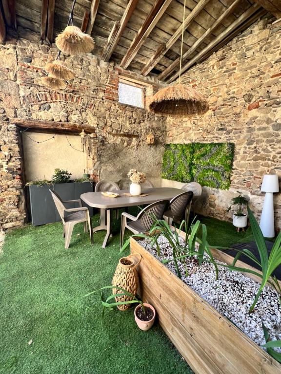 a patio with a table and chairs and a stone wall at Cozy independent apartment in Mornant