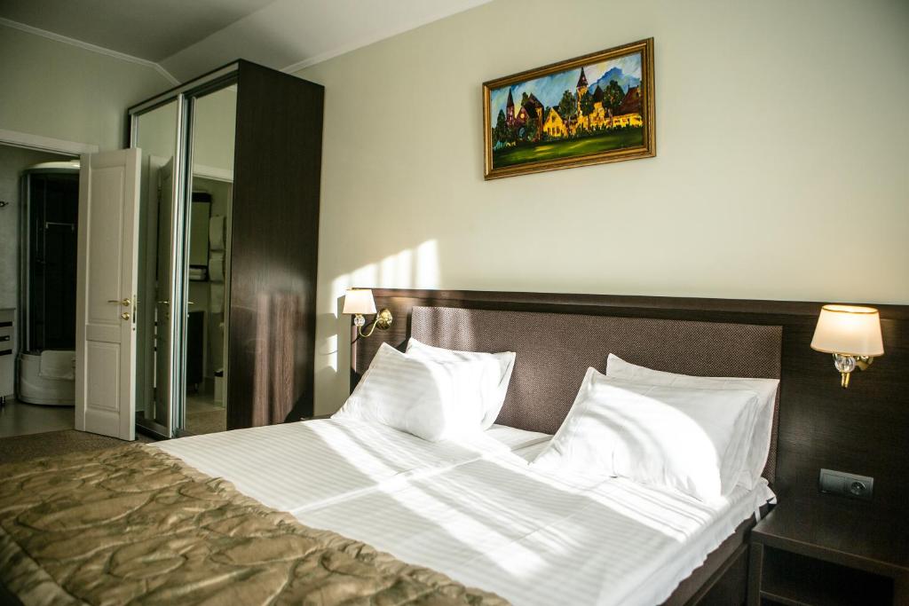 a bed in a bedroom with a picture on the wall at Churchill-Inn in Vinnytsya