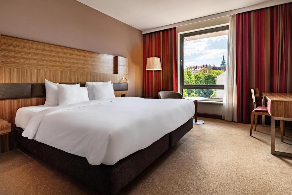 a large white bed in a hotel room with a window at Radisson Blu Hotel Krakow in Krakow