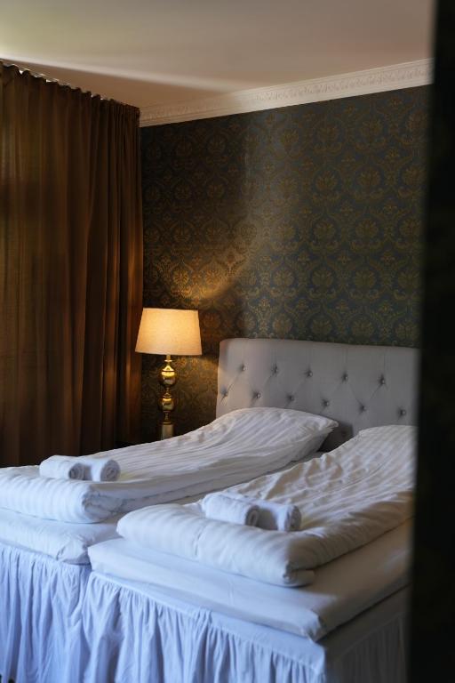 Zwei Einzelbetten in einem Schlafzimmer mit Lampe in der Unterkunft Centralhotellet Söderhamn in Söderhamn